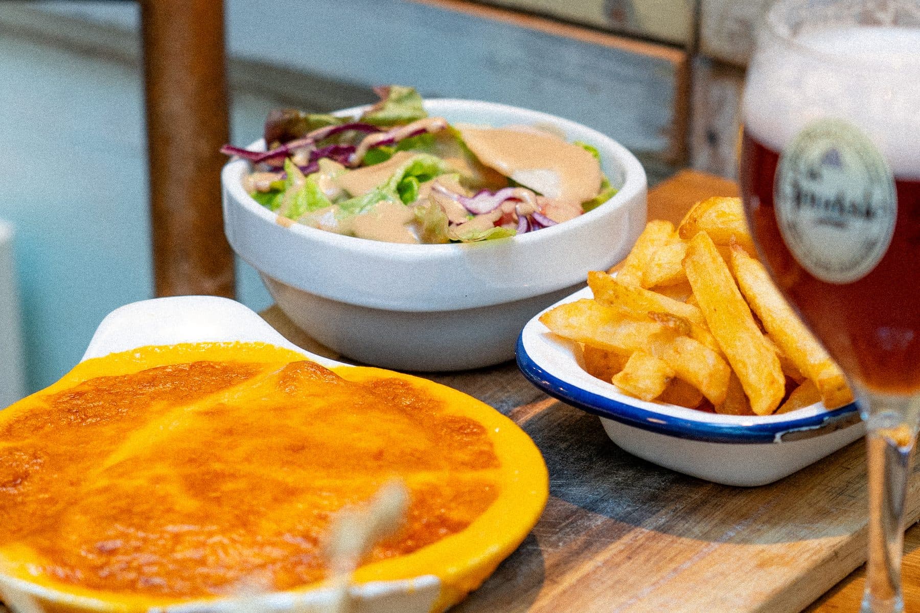 Un welsh servi avec ses frites et sa salade, sur une table de bois